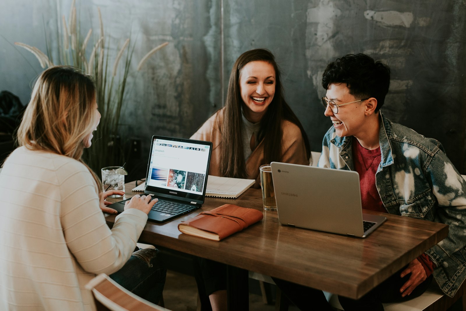 Tres jóvenes colaborando alrededor de una mesa con laptops