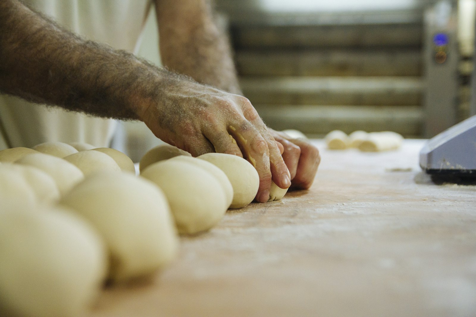 Panadero formando bollos de pan en una panadería
